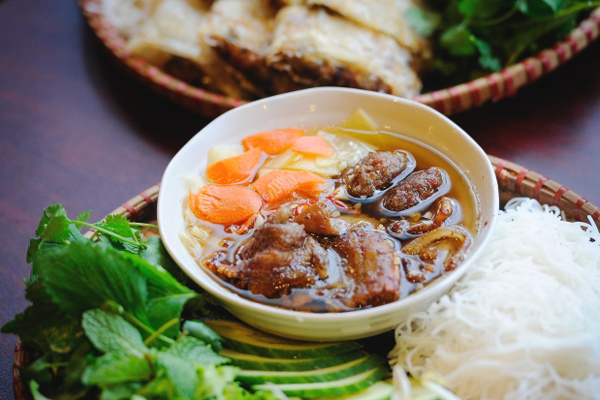 fish sauce broth with pork belly, noodles and leafy greens