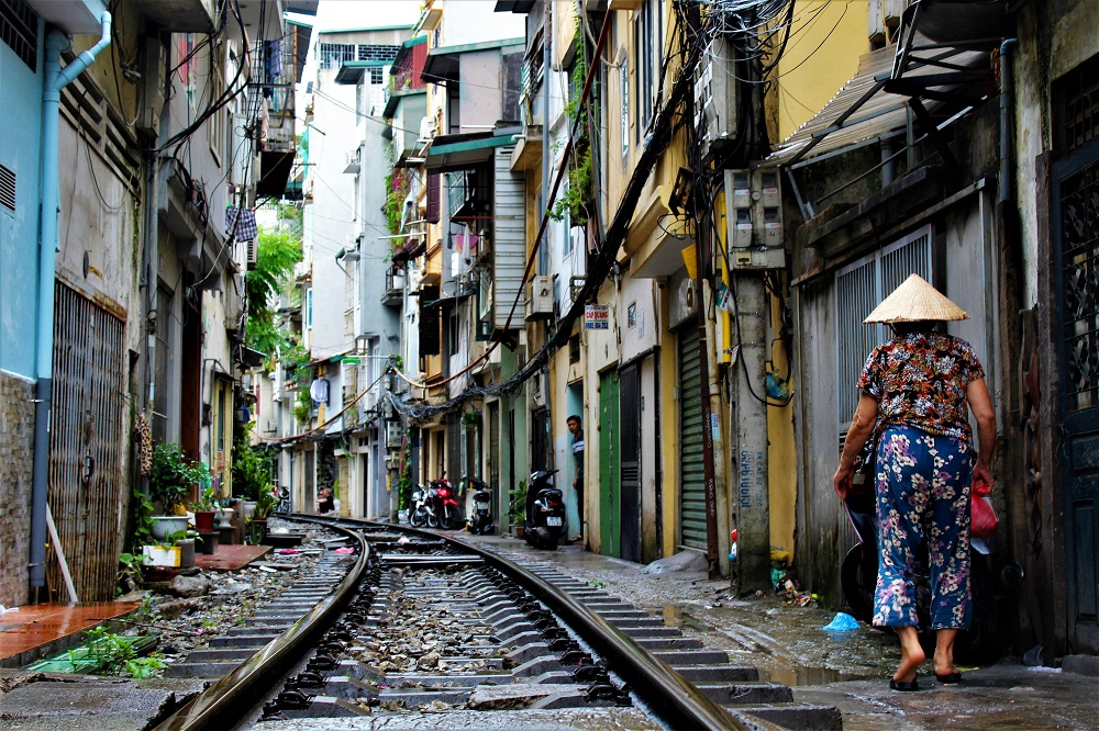 A Vietnamese woman walking along a street beside a railway track